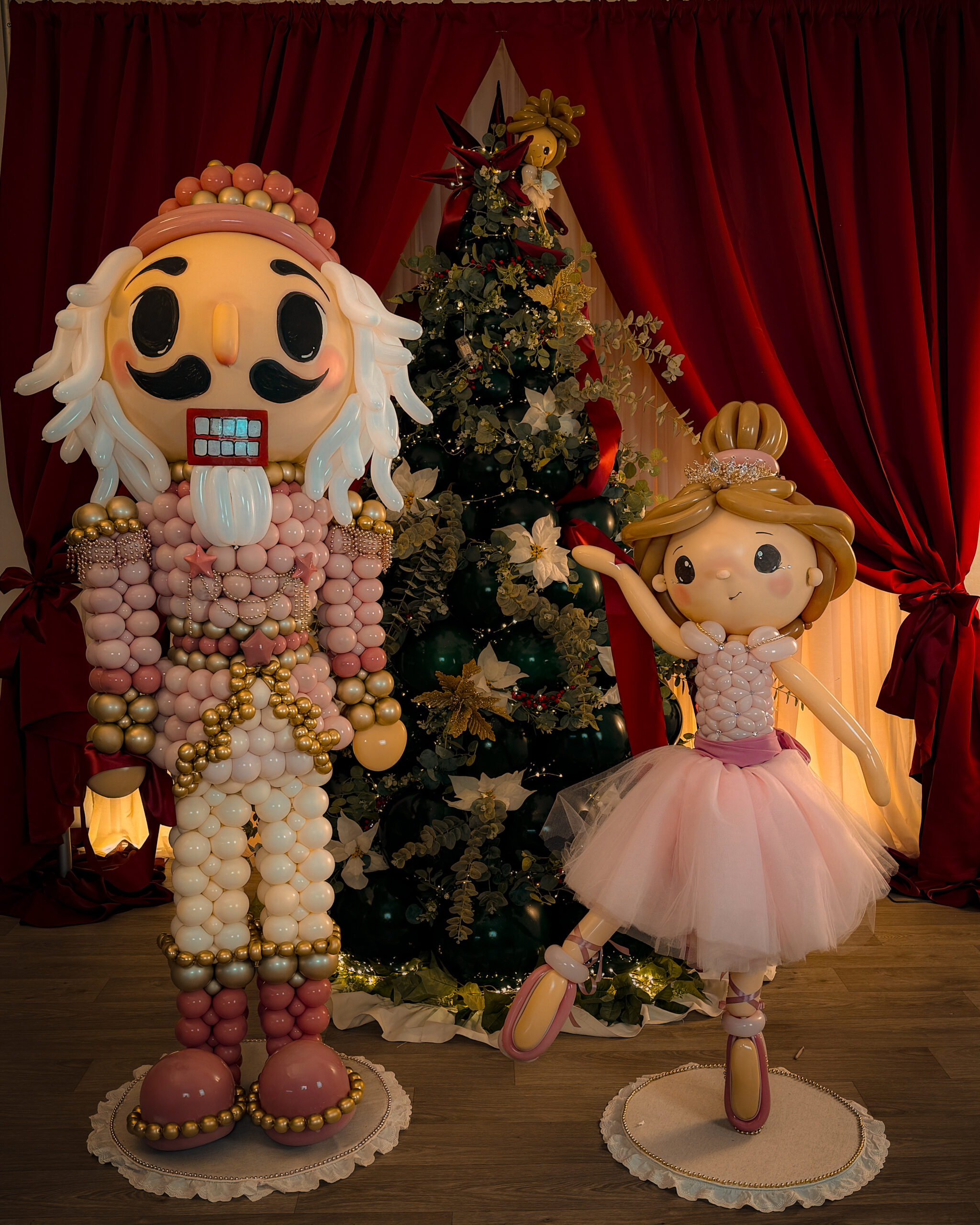 Cascanueces rosa y bailarina de globos junto a un árbol de Navidad