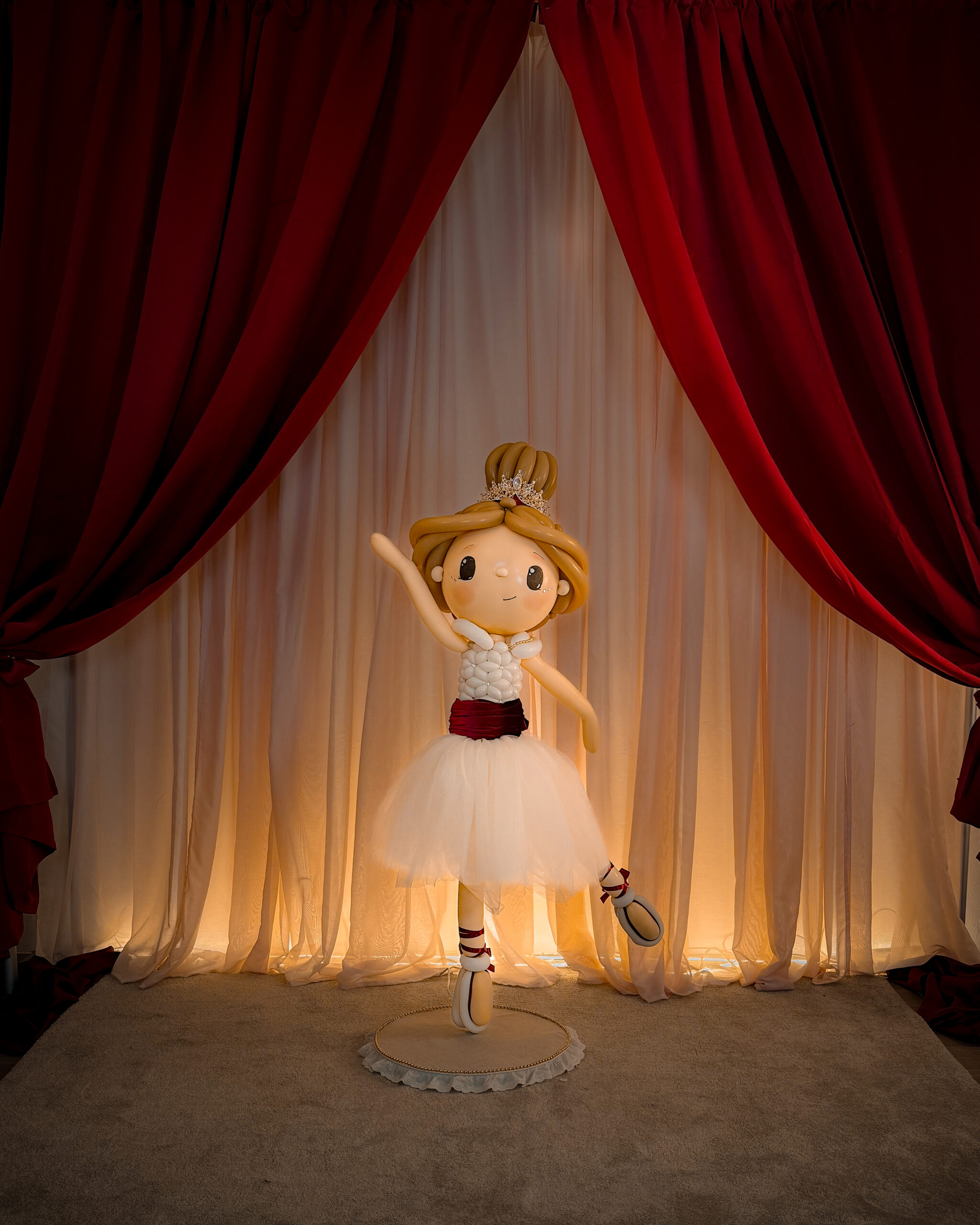 Figura de bailarina creada con globos sobre un escenario navideño
